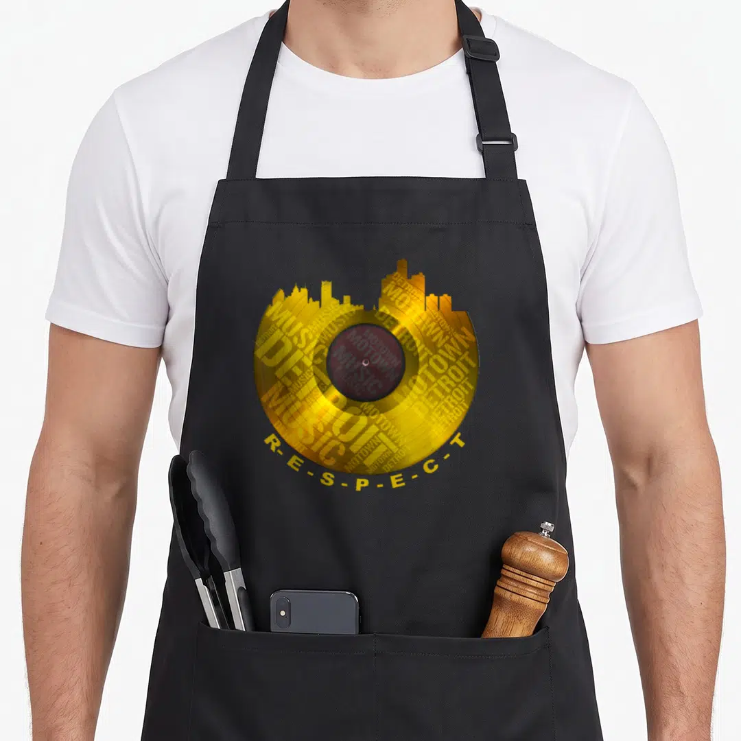 Respect detroit apron - Gold vinyl record with Detroit skyline and R-E-S-P-E-C-T text — shown on a black cotton canvas apron against a white background