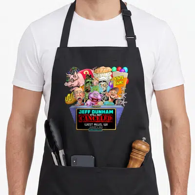 West wi aprons - Jeff Dunham Still Not Canceled cartoon puppets fair food grey stage red green yellow purple — shown on a black cotton canvas apron against a white background