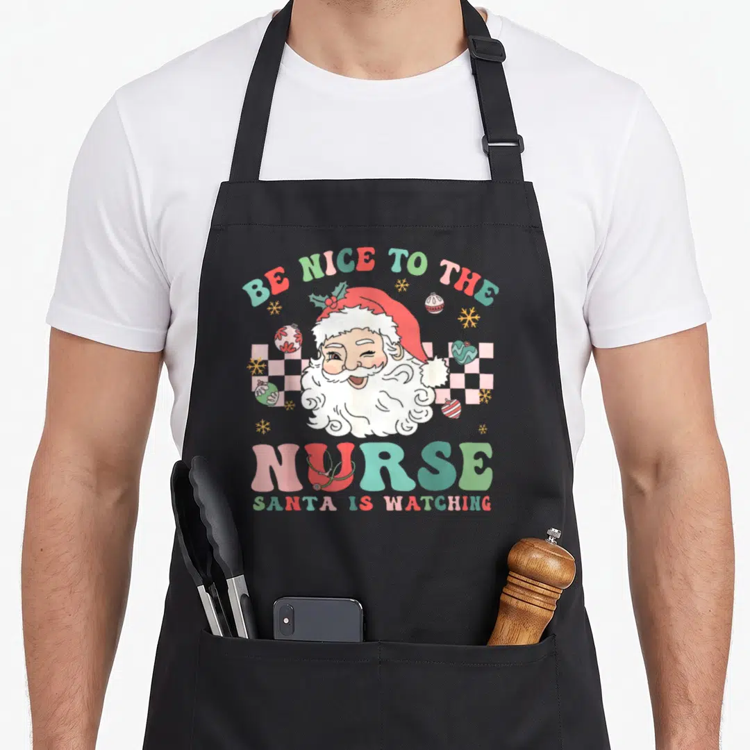 Nurse christmas santa apron - Cartoon Santa winking with stethoscope on U of NURSE, checkerboard background, scattered — shown on a black cotton canvas apron against a white background