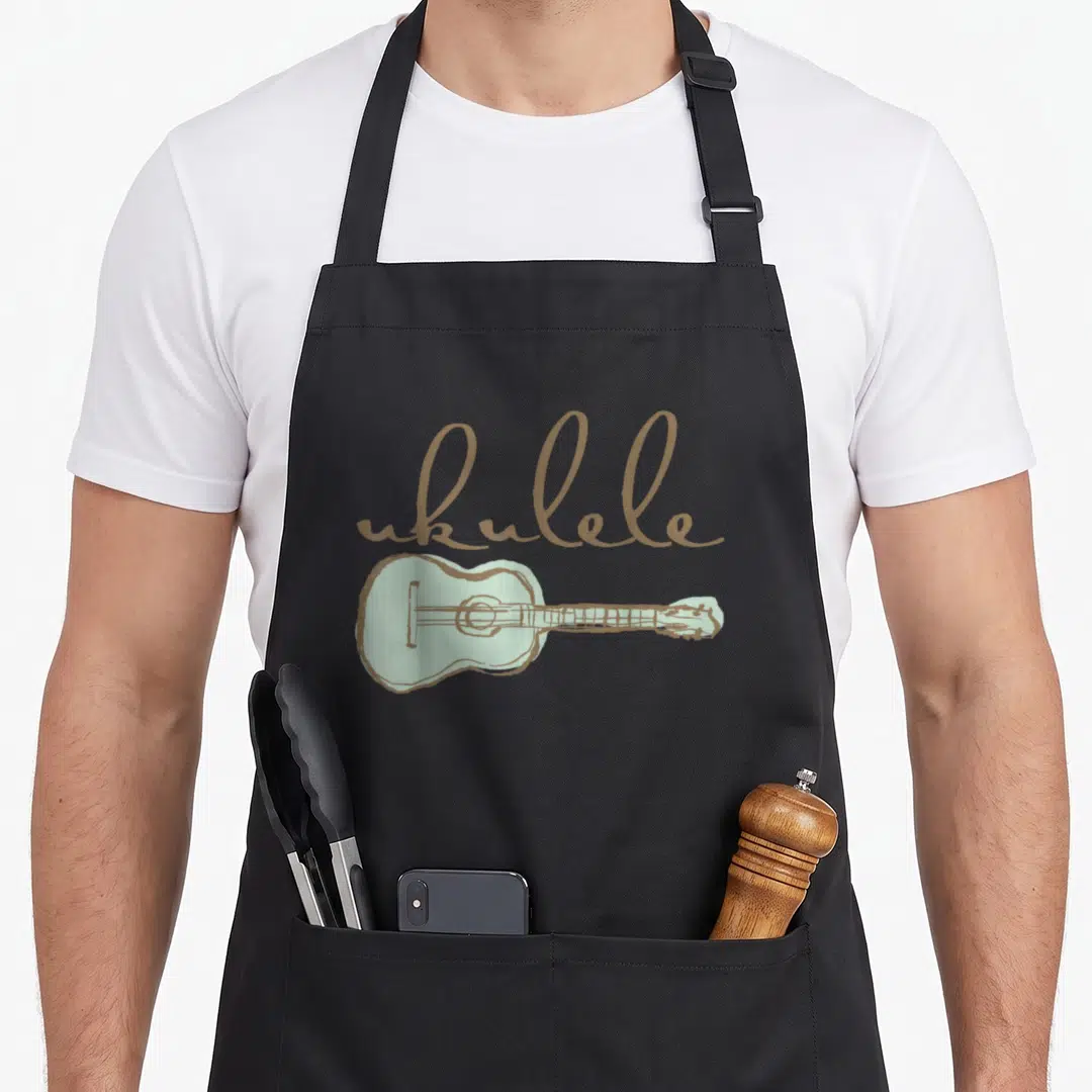 Guitarist ukulele apron - Tan script reading ukulele above a light green simplified ukulele drawing — shown on a black cotton canvas apron against a white background
