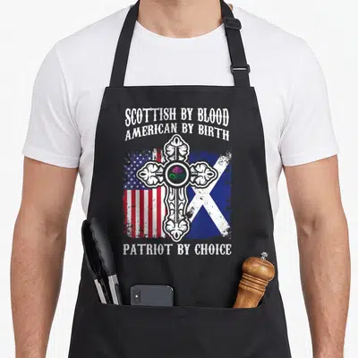 Scottish blood apron - Celtic cross with thistle over distressed US and Scottish flags with stacked text — shown on a black cotton canvas apron against a white background