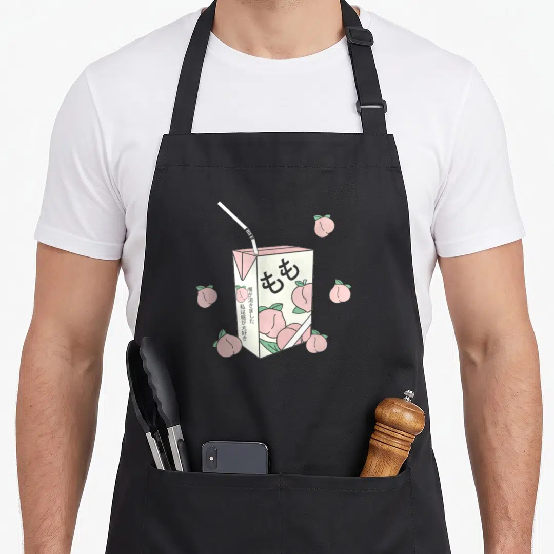 90s anime apron - Peach juice box with Japanese text surrounded by pink fruit in cartoon style — shown on a black cotton canvas apron against a white background