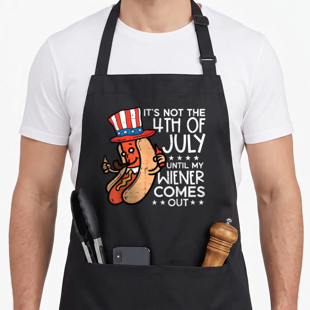 Wiener 4th of july apron - Cartoon hot dog in patriotic hat holding mustard and pipe with white pun text — shown on a black cotton canvas apron against a white background