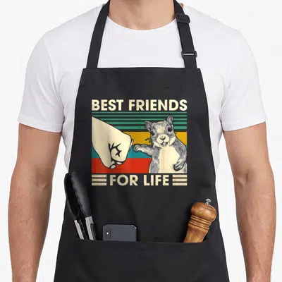 Squirrel friends apron - Retro squirrel and human fist bump with striped background and text best friends for life — shown on a black cotton canvas apron against a white background