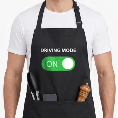 Mode driving apron - Green toggle switch with ON text and white button below DRIVING MODE label — shown on a black cotton canvas apron against a white background