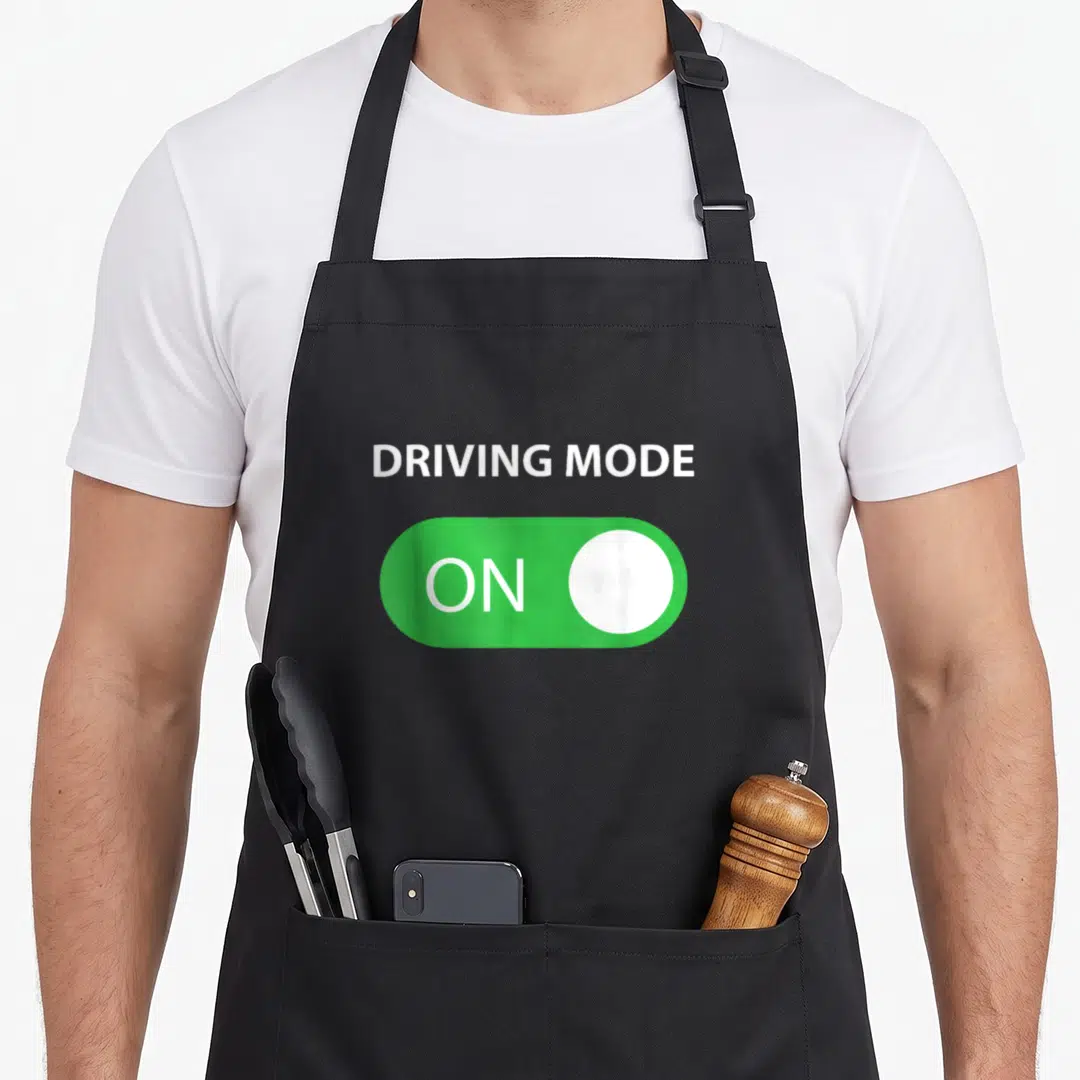 Mode driving apron - Green toggle switch with ON text and white button below DRIVING MODE label — shown on a black cotton canvas apron against a white background