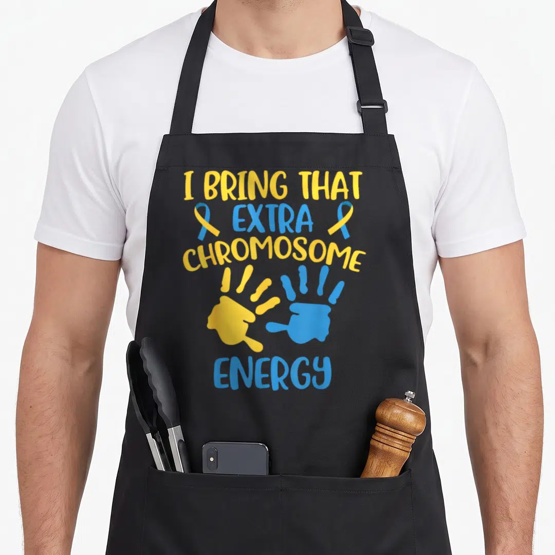 Chromosome an extra apron - I Bring That Extra Chromosome Energy text with yellow blue handprints and ribbons — shown on a black cotton canvas apron against a white background
