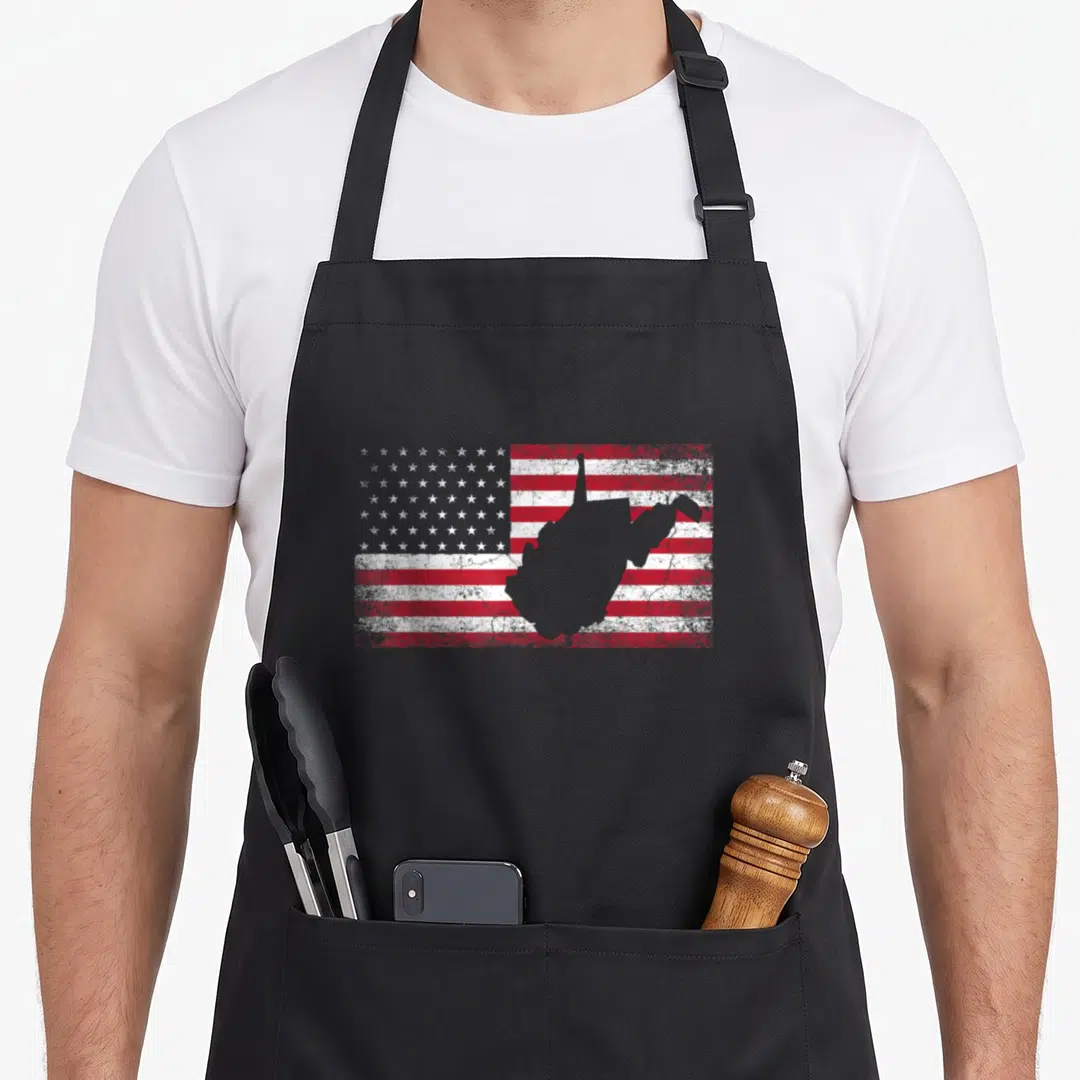 West 4th of july apron - Grey West Virginia silhouette over distressed red white blue USA flag pattern — shown on a black cotton canvas apron against a white background