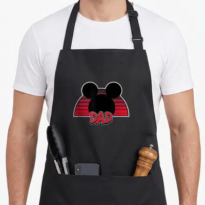 Vintage mouse dad apron - Black Mickey Mouse head over red grey stripes with DAD text in bold font — shown on a black cotton canvas apron against a white background