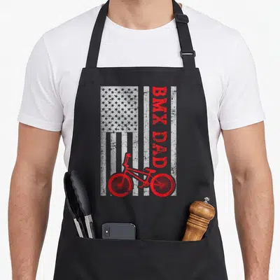 Bmx father day apron - Red BMX bike and vertical BMX DAD text on distressed white flag background — shown on a black cotton canvas apron against a white background