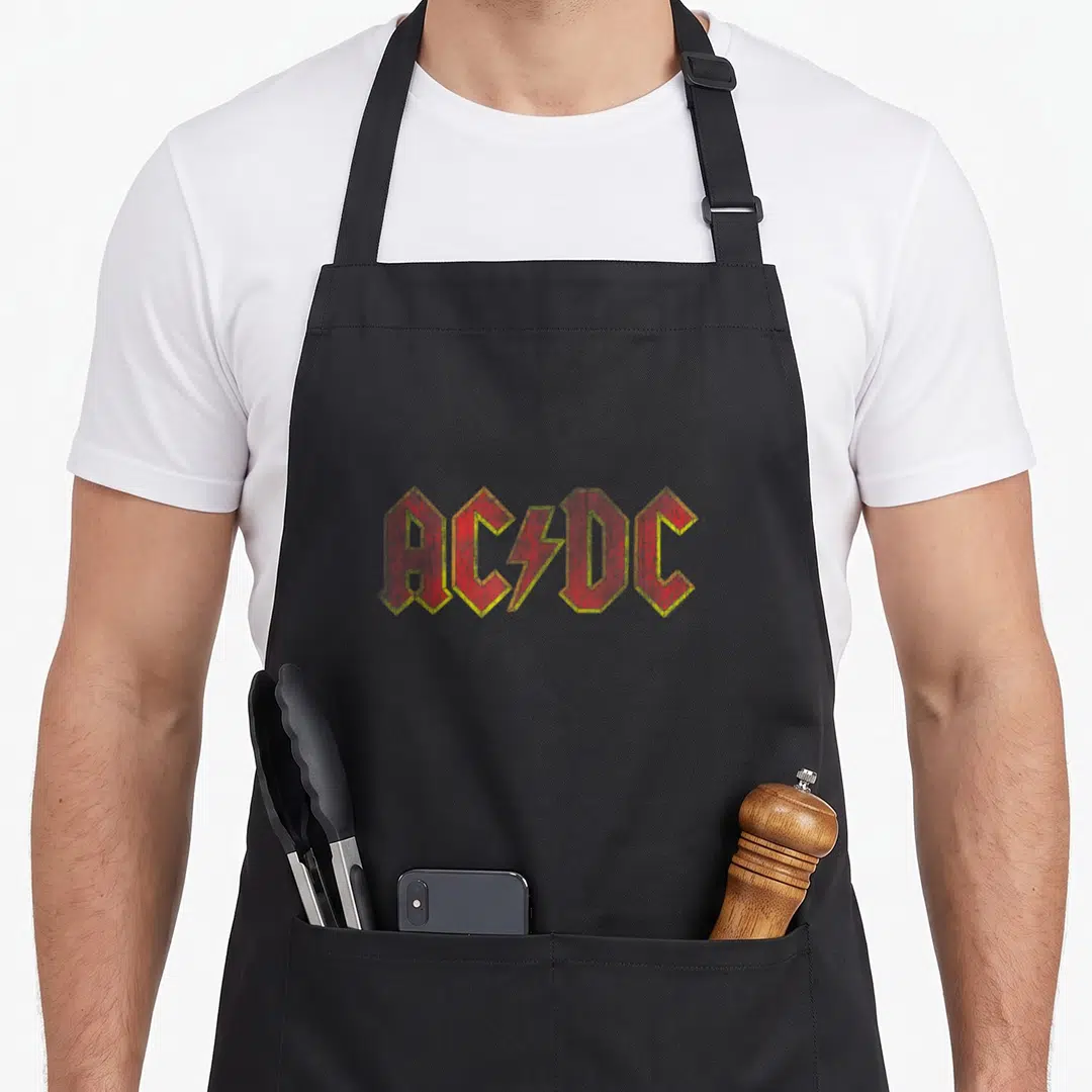 Band distressed apron - Red and yellow ACDC logo with lightning bolt divider in distressed print style — shown on a black cotton canvas apron against a white background