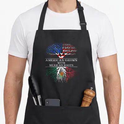 Grown mexican apron - Tree with US and Mexican flag colors and roots surrounding centered text — shown on a black cotton canvas apron against a white background