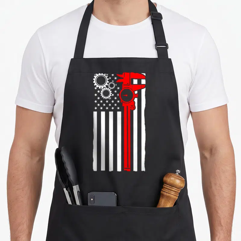 Flag machinist apron - Red caliper and white gears on white flag stripes minimalist design — shown on a black cotton canvas apron against a white background