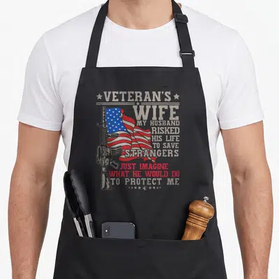 Boot wife apron - Distressed American flag and rifle with text honoring a veteran's wife and protective sacrifice — shown on a black cotton canvas apron against a white background