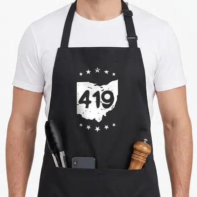 Sandusky pride apron - White Ohio map silhouette containing grey 419 text with two rows of five stars above and below — shown on a black cotton canvas apron against a white background