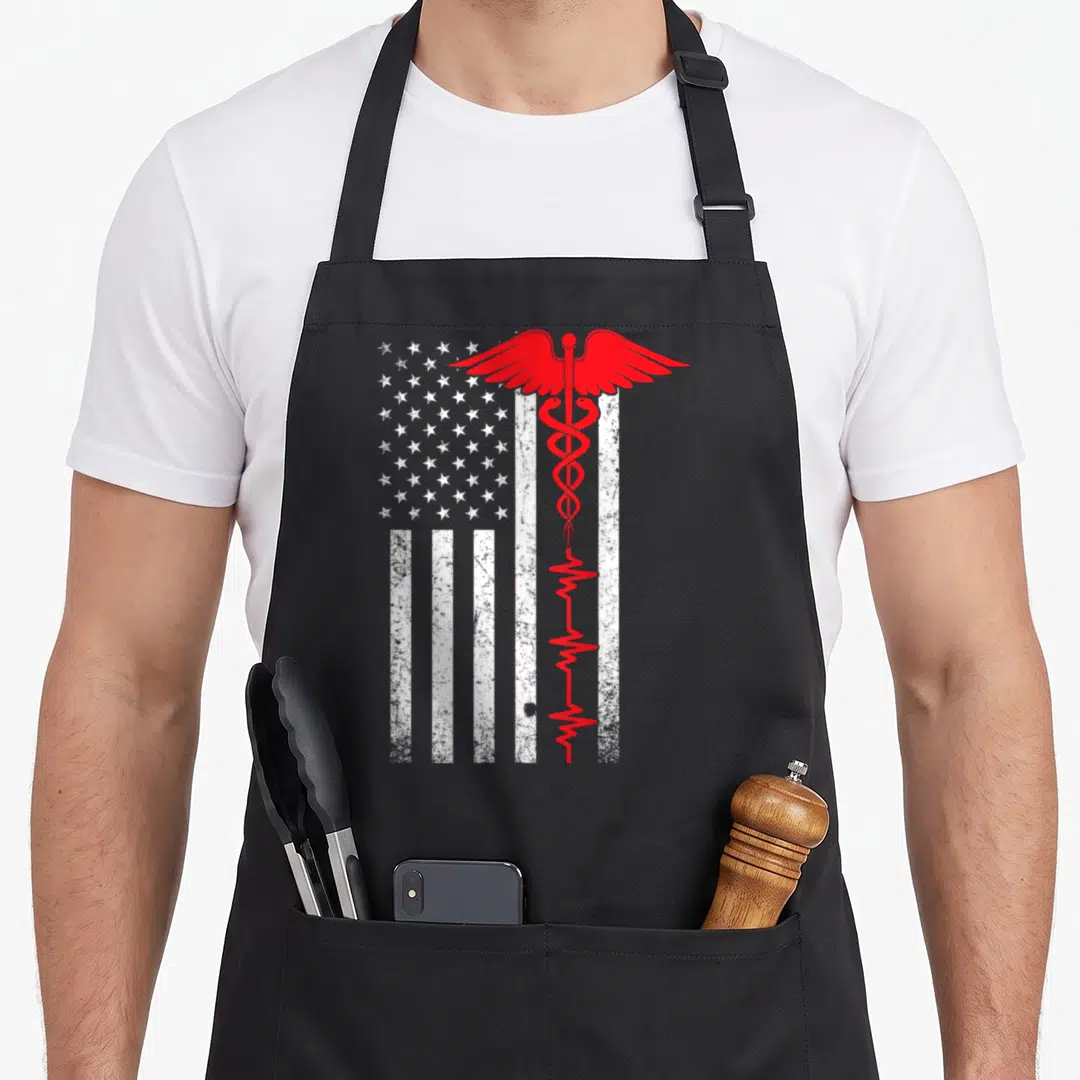 Thin nurse apron - Red caduceus and heartbeat line over distressed white USA flag — shown on a black cotton canvas apron against a white background