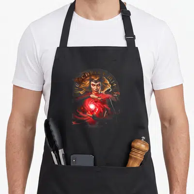 Glowing doctor apron - Realistic Scarlet Witch holding red magic energy with gold circular text border — shown on a black cotton canvas apron against a white background