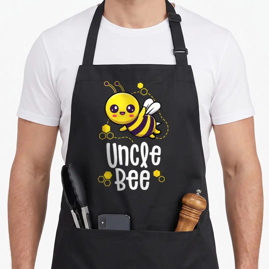 Uncle bee aprons - Cartoon bee with yellow honeycomb cells and white Uncle Bee text — shown on a black cotton canvas apron against a white background