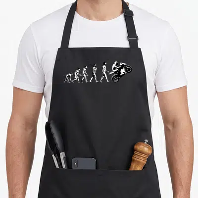 Race bike apron - White evolution of man sequence ending in motorcycle wheelie silhouette — shown on a black cotton canvas apron against a white background