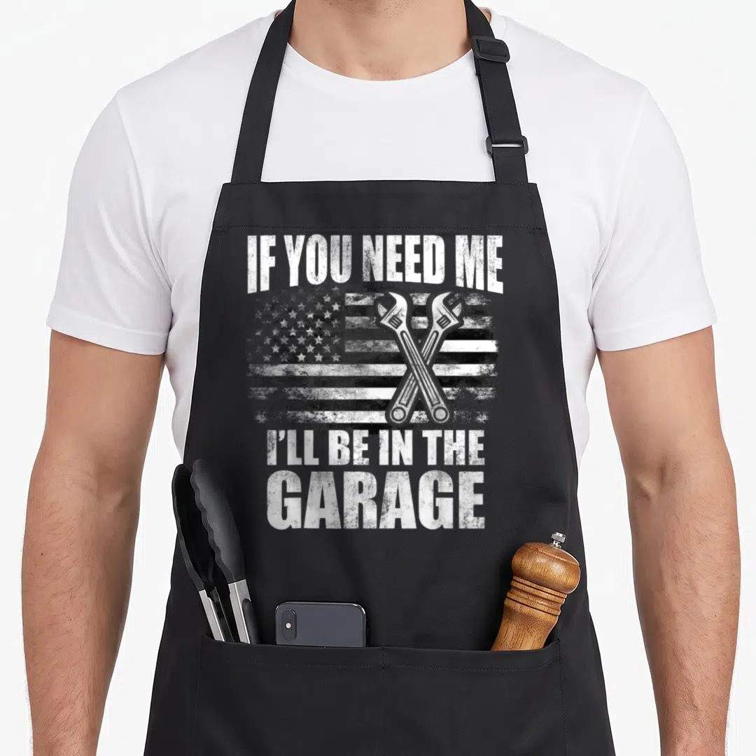 Car mechanic garage apron - Distressed US flag with crossed wrenches and garage text in greyscale — shown on a black cotton canvas apron against a white background