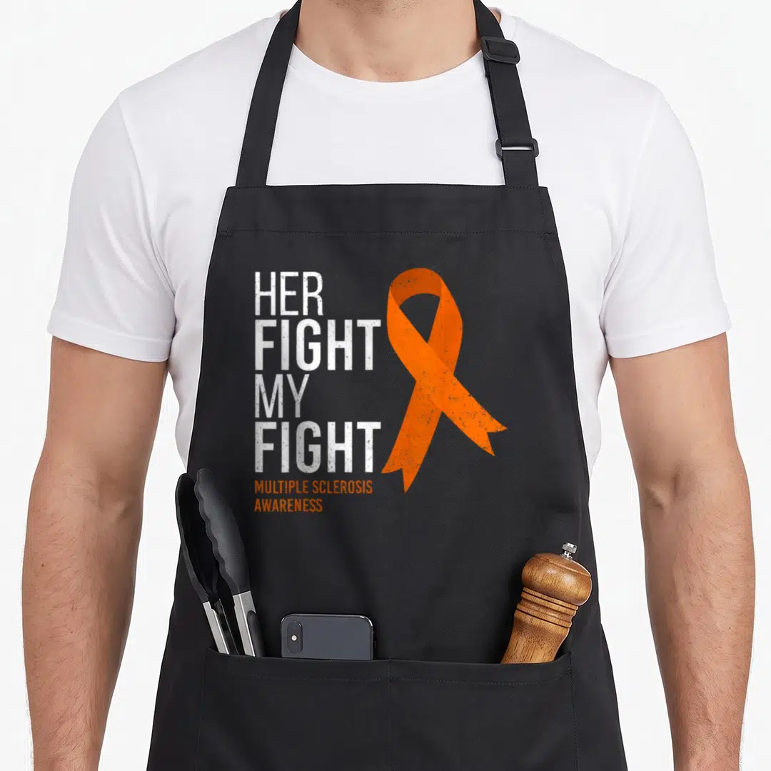 Fight msemen apron - Stacked white text Her Fight My Fight next to orange MS awareness ribbon — shown on a black cotton canvas apron against a white background