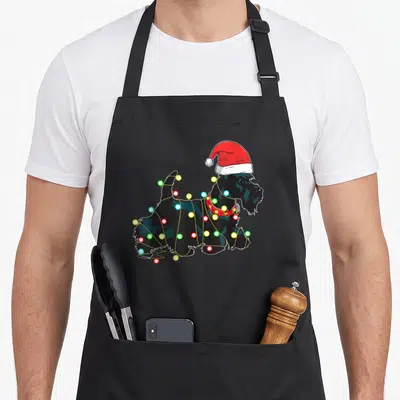 Scottie dog christmas lights apron - Black dog in red santa hat wrapped in multicolored light bulbs — shown on a black cotton canvas apron against a white background