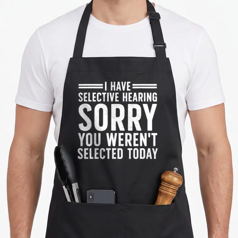 Funny sarcasm sarcastic apron - White stacked text reading I have selective hearing sorry you weren't selected today — shown on a black cotton canvas apron against a white background