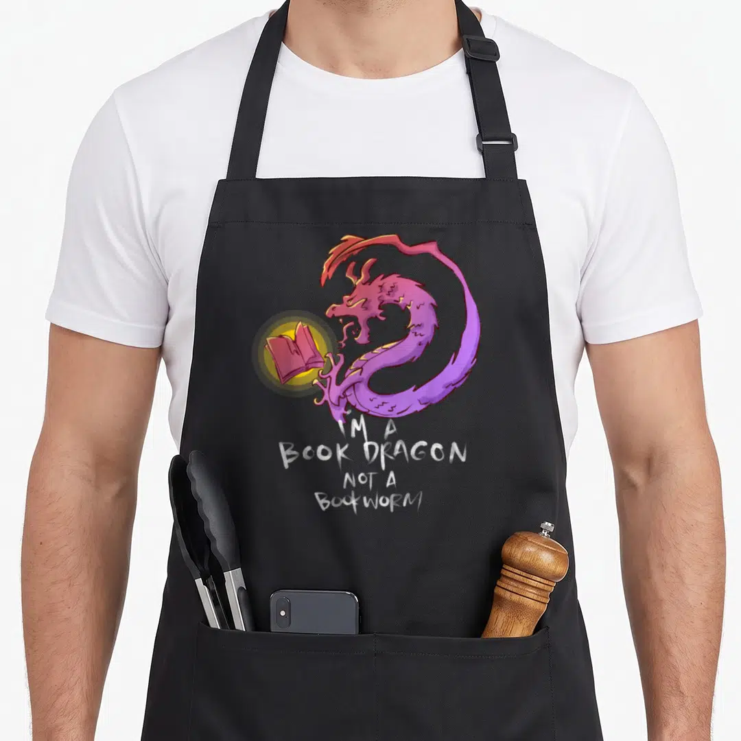 Bookish dragon apron - Purple dragon curled around glowing book with white text I'M A BOOK DRAGON NOT A BOOKWORM — shown on a black cotton canvas apron against a white background