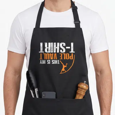 Vaulting pole apron - Inverted white and orange text reading THIS IS MY POLE VAULT T-SHIRT with athlete silhouette — shown on a black cotton canvas apron against a white background