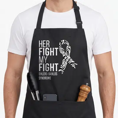Fight zebra dad apron - White distressed text reading Her Fight My Fight next to a black and white zebra awareness — shown on a black cotton canvas apron against a white background