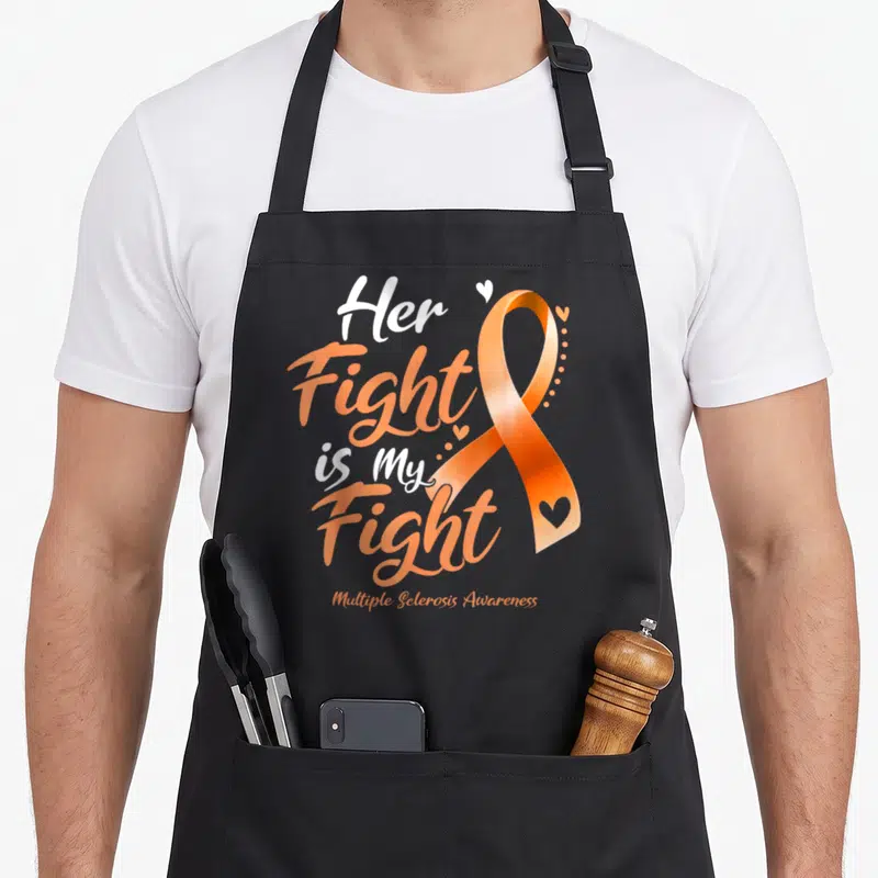 Multiple msemen apron - Her Fight Is My Fight text next to an orange ribbon with small white hearts — shown on a black cotton canvas apron against a white background