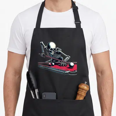 Snooker halloween apron - Realistic skeleton leaning over red pool table holding cue and aiming at balls — shown on a black cotton canvas apron against a white background