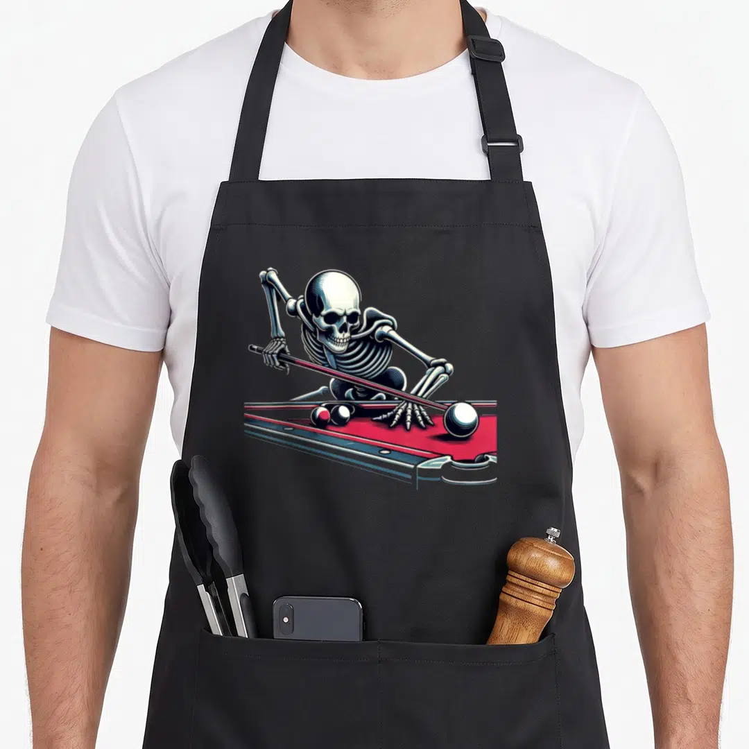 Snooker halloween apron - Realistic skeleton leaning over red pool table holding cue and aiming at balls — shown on a black cotton canvas apron against a white background