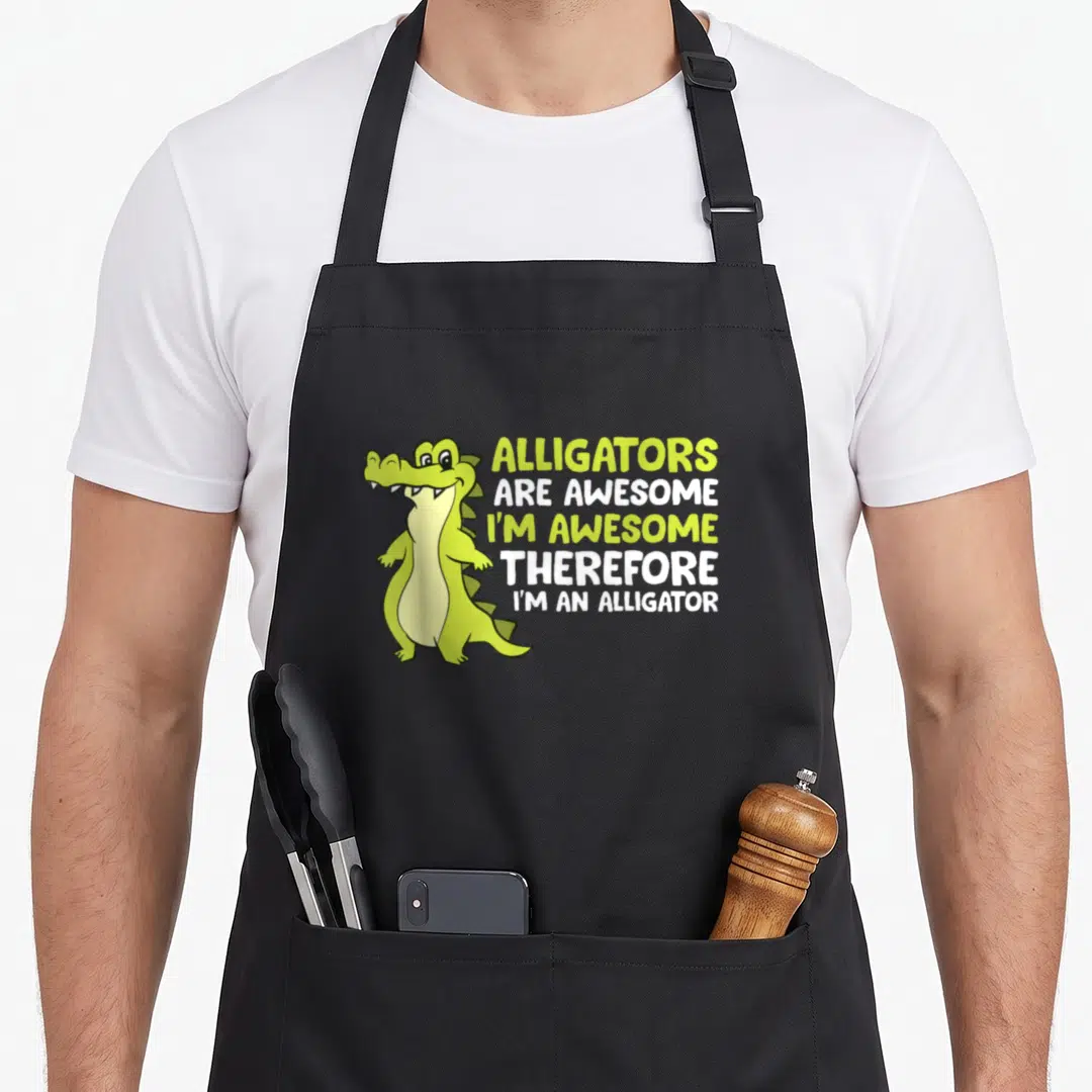 Cute alligator apron - Lime green cartoon alligator standing next to stacked white and lime text reading Alligators Are — shown on a black cotton canvas apron against a white background