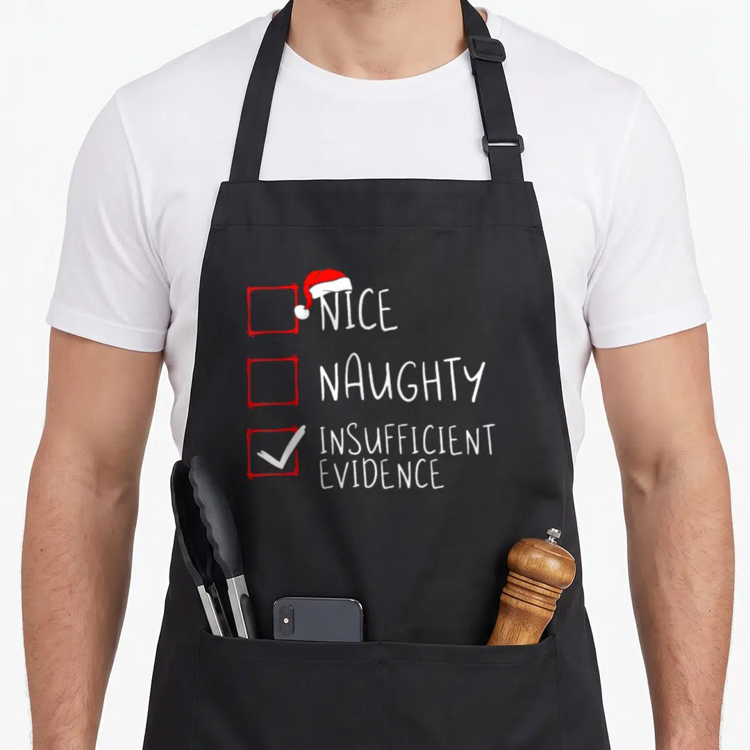 Naughty santa claus apron - Red checkboxes with white text reading Nice Naughty Insufficient Evidence and a Santa hat — shown on a black cotton canvas apron against a white background