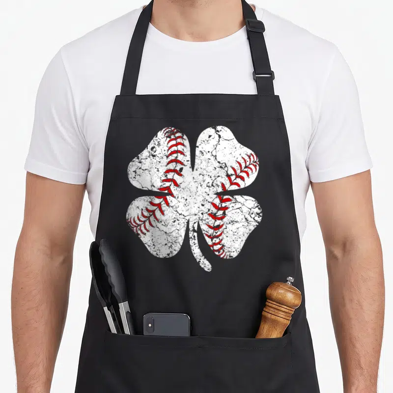 Baseball st patrick day aprons - White distressed four-leaf clover with red baseball stitching on black fabric — shown on a black cotton canvas apron against a white background