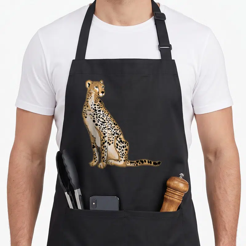 Illustration cheetah apron - Seated cartoon cheetah in tan and black spots facing right on grey background — shown on a black cotton canvas apron against a white background