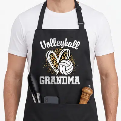 Grandma leopard apron - Volleyball GRANDMA text with leopard heart and ball graphic — shown on a black cotton canvas apron against a white background