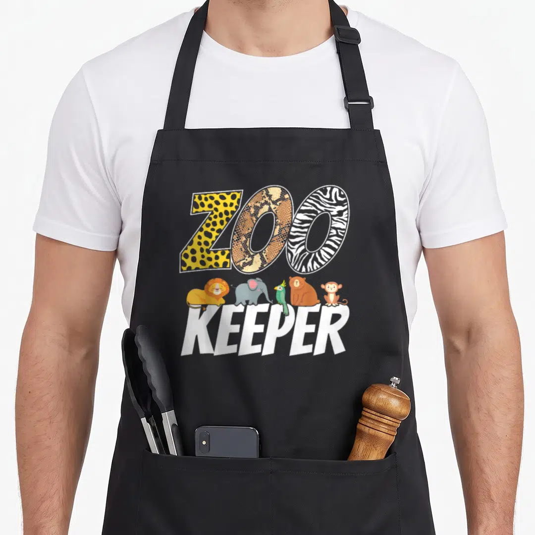 Animal african apron - ZOO KEEPER text with five cartoon animals including lion elephant parrot bear monkey and animal — shown on a black cotton canvas apron against a white background