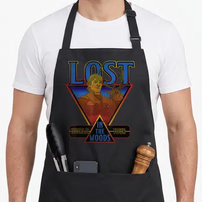 Frozen wood apron - Retro LOST IN THE WOODS WORLD TOUR text with man and deer in geometric triangles — shown on a black cotton canvas apron against a white background