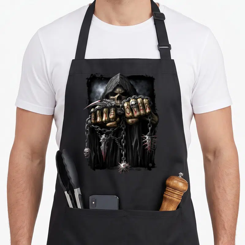 Spiral gothic apron - Grim Reaper with GAME OVER on knuckles, chains, pentagram dagger, and spikes — shown on a black cotton canvas apron against a white background