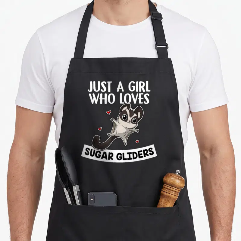 Glider sugar apron - Cartoon sugar glider with red hearts and text JUST A GIRL WHO LOVES SUGAR GLIDERS — shown on a black cotton canvas apron against a white background