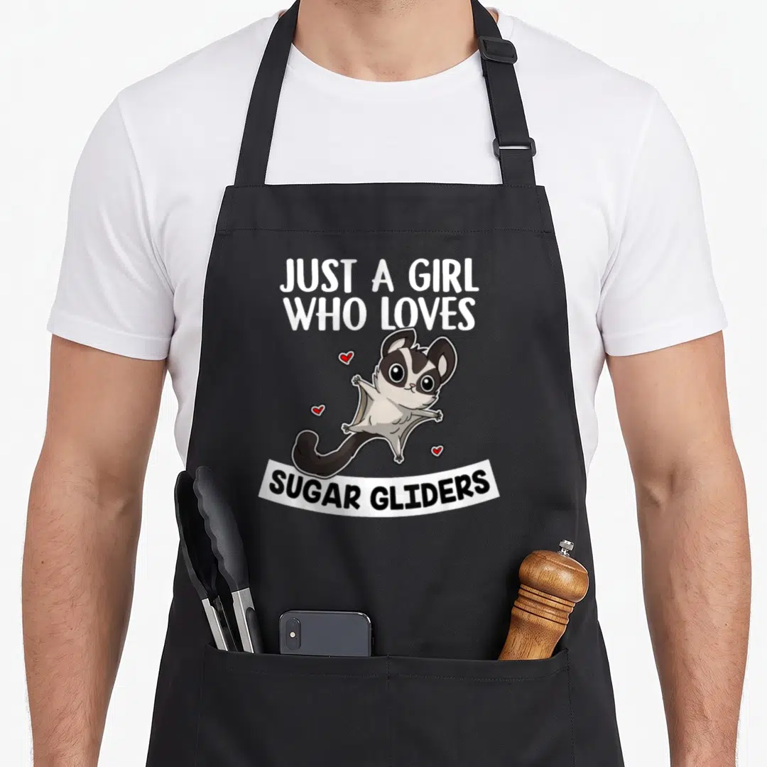 Glider sugar apron - Cartoon sugar glider with red hearts and text JUST A GIRL WHO LOVES SUGAR GLIDERS — shown on a black cotton canvas apron against a white background