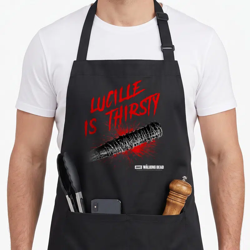 Lucille walking apron - LUCILLE IS THIRSTY red text above black barbed wire bat and red splatter — shown on a black cotton canvas apron against a white background