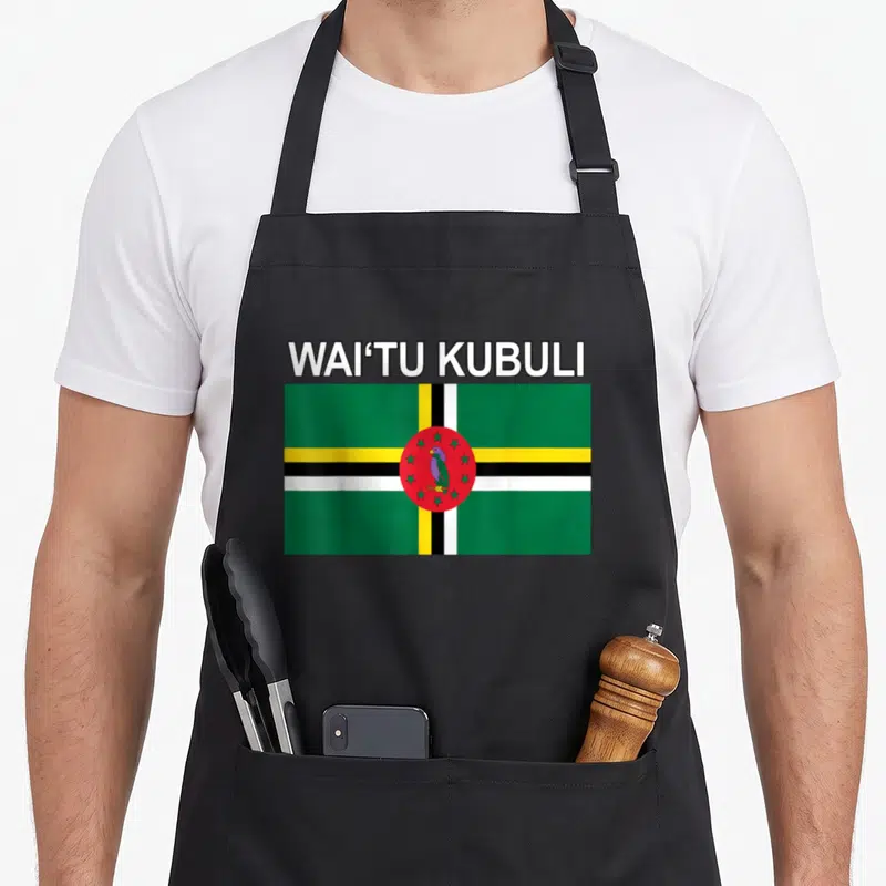Waitu island pride apron - WAI'TU KUBULI text above a rectangular Dominica flag with green white yellow and red colors — shown on a black cotton canvas apron against a white background