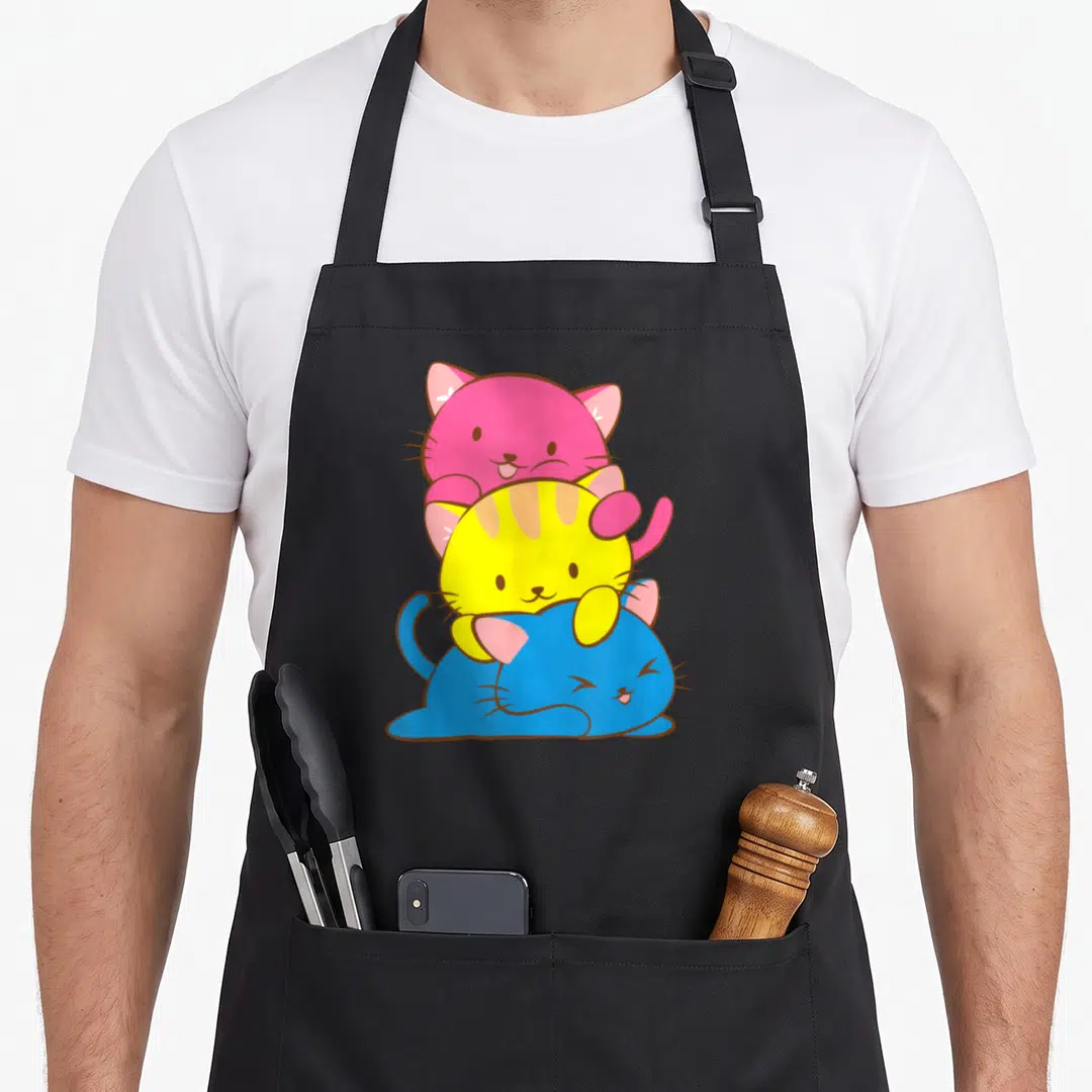 Pansexual kawaii cooking apron - Three stacked cartoon cats in pink, yellow, and blue representing pansexual pride — shown on a black cotton canvas apron against a white background
