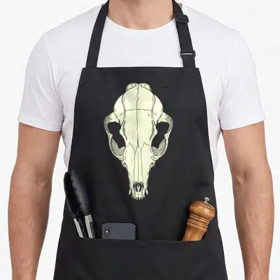 Culture goth apron - Cream line-art animal skull illustration on a grey background — shown on a black cotton canvas apron against a white background