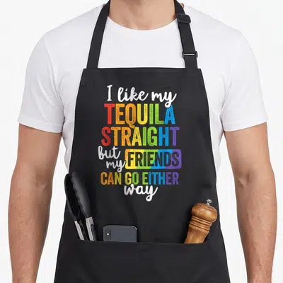 Lgbt friends apron - Rainbow typography reading I like my TEQUILA STRAIGHT but my FRIENDS CAN GO EITHER way — shown on a black cotton canvas apron against a white background