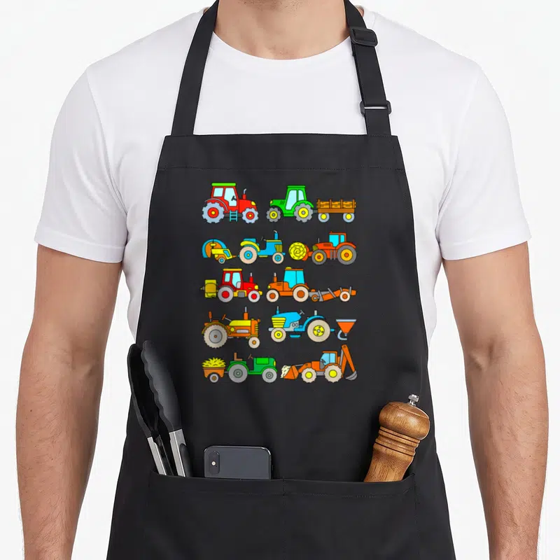 Toddler farm apron - Ten cartoon tractors in red, green, blue, orange, and yellow arranged in five rows of two — shown on a black cotton canvas apron against a white background