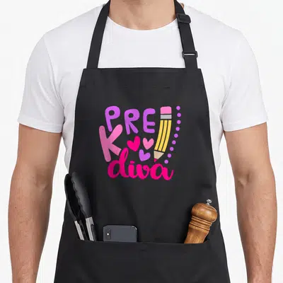 Diva day pre k apron - PRE K diva text with pencil, hearts, and dots in purple, pink, and yellow — shown on a black cotton canvas apron against a white background
